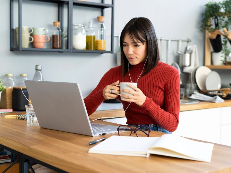 Frau im Home Office vor dem Laptop mit Teetasse