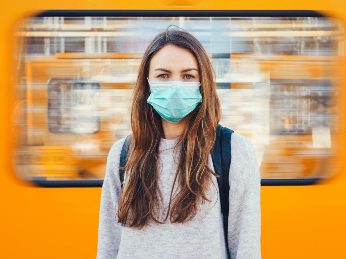 Frau mit Corona Maske vor Bahn