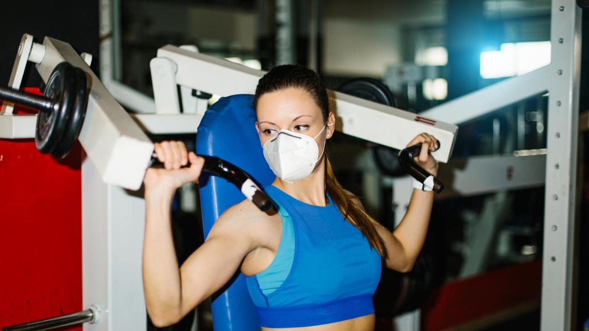 frau gym maske mundschutz gewichte sport fitness muskeln