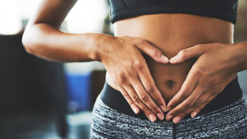 sportliche Frau hält sich die Hände vor den Bauch