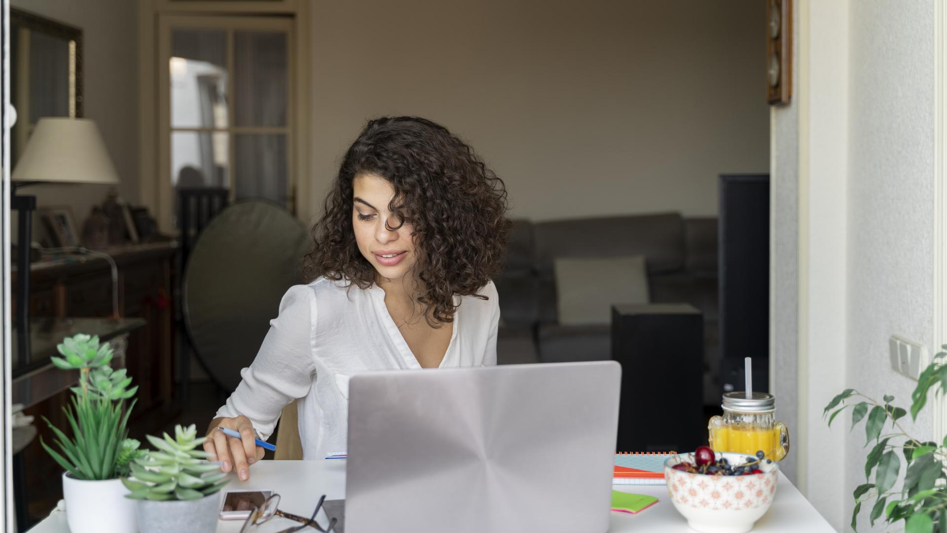 Young woman using cell phone and laptop at desk model