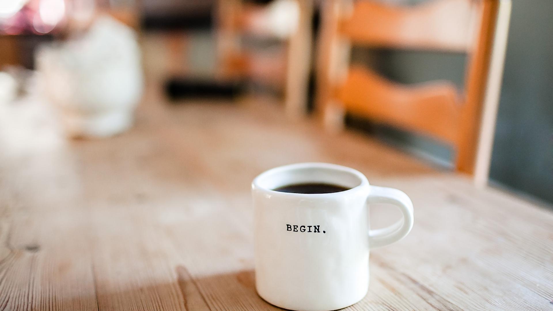 Tasse auf dem Holztisch mit der Aufschrift begin