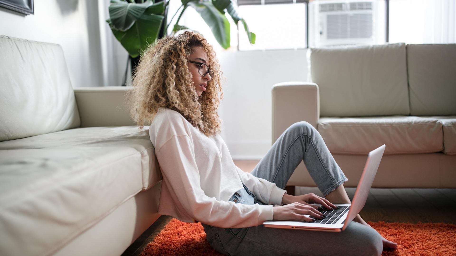 Frau mit Afro-Locken und schicker Business-Kleidung angelehnt an eine Couch