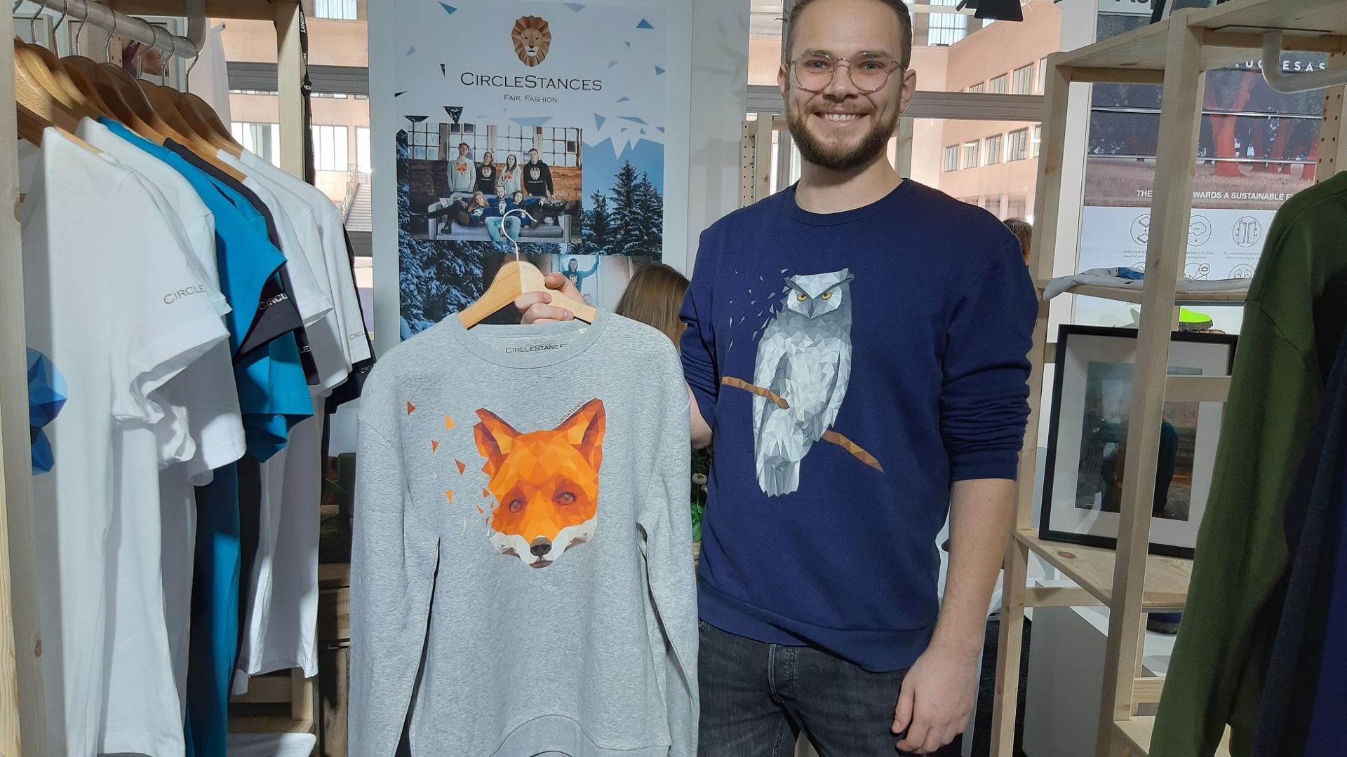 lächelnder Mann mit blauem Pullover und grauem Pullover mit Fuchsprint