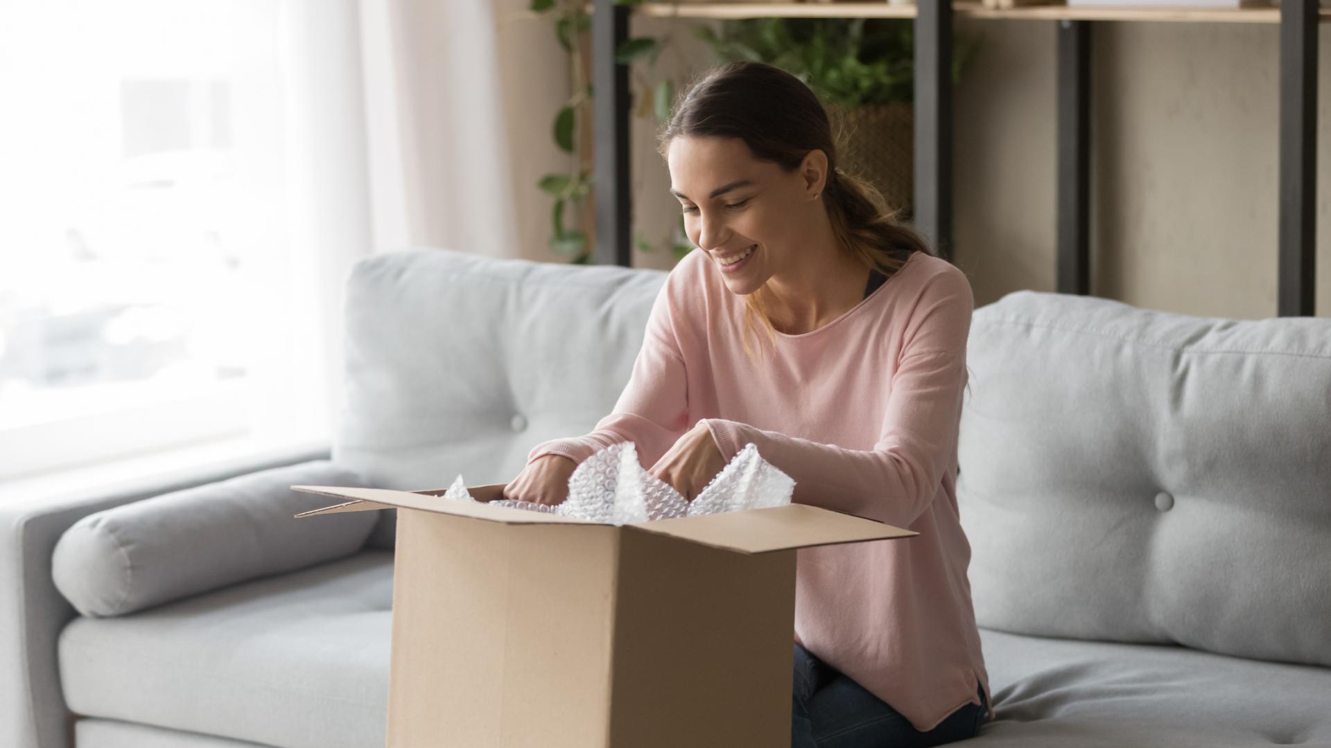 Frau auf der Couch packt Paket