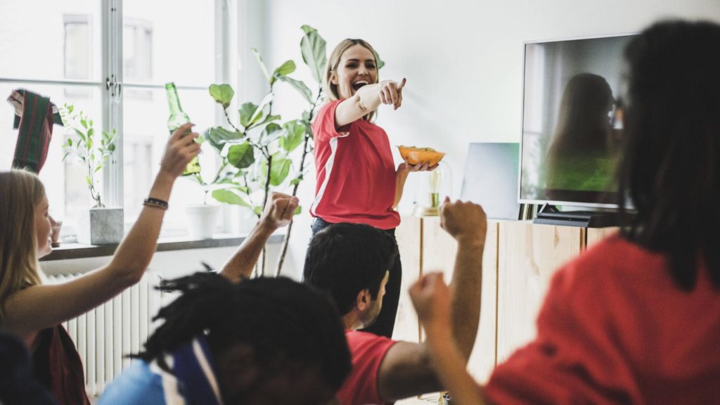 Frau zeigt auf Freunde jubeln spiele snacks