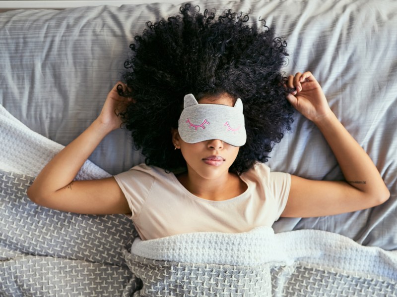 Shot of a young woman sleeping with a mask on in bed