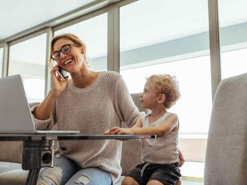 Eine Frau telefoniert. Daneben sitzt ein Kleinkind.