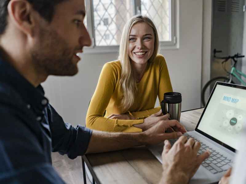 frau sitzt mit mann am tisch mit laptop