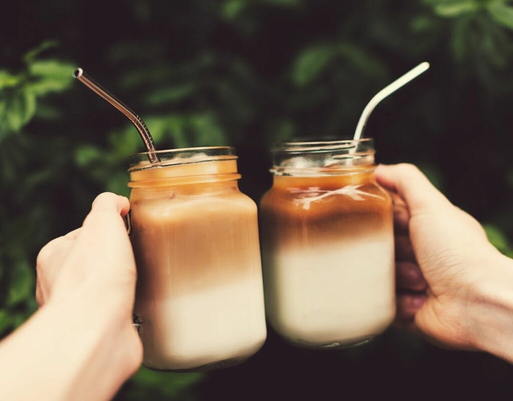 zwei hände halten eiskaffee mit koffein