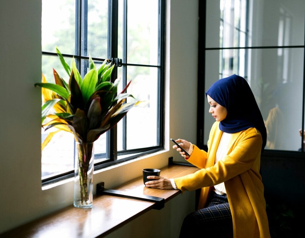 frau mit hijab im cafe mit smartphone