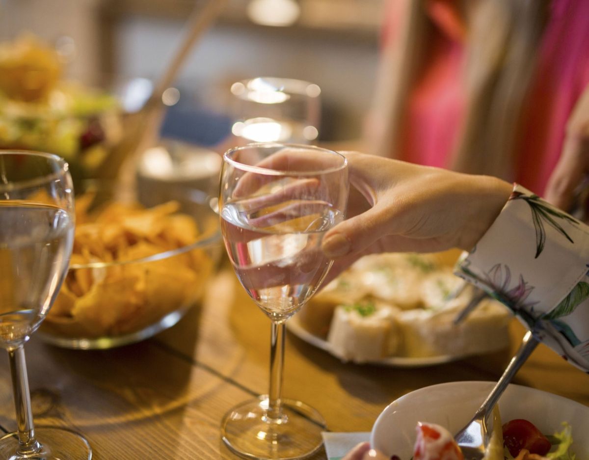 Hände mit Weinglas am gedeckten Tisch