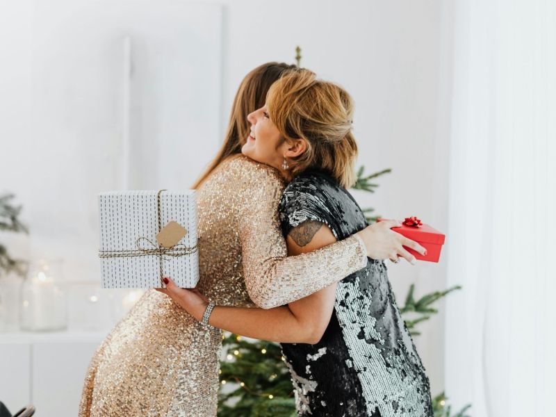 Zwei Frauen mit Geschenken umarmen sich zu Weihnachten