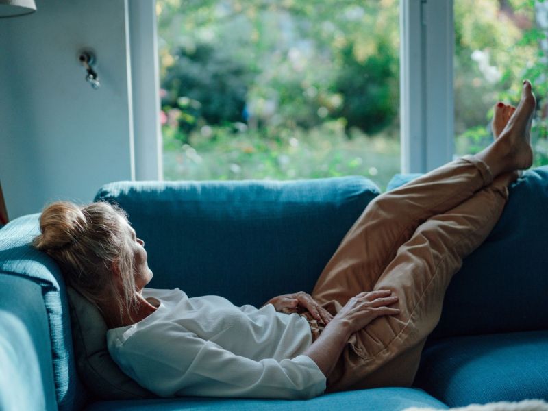 Frau liegt auf Sofa und schaut aus dem Fenster