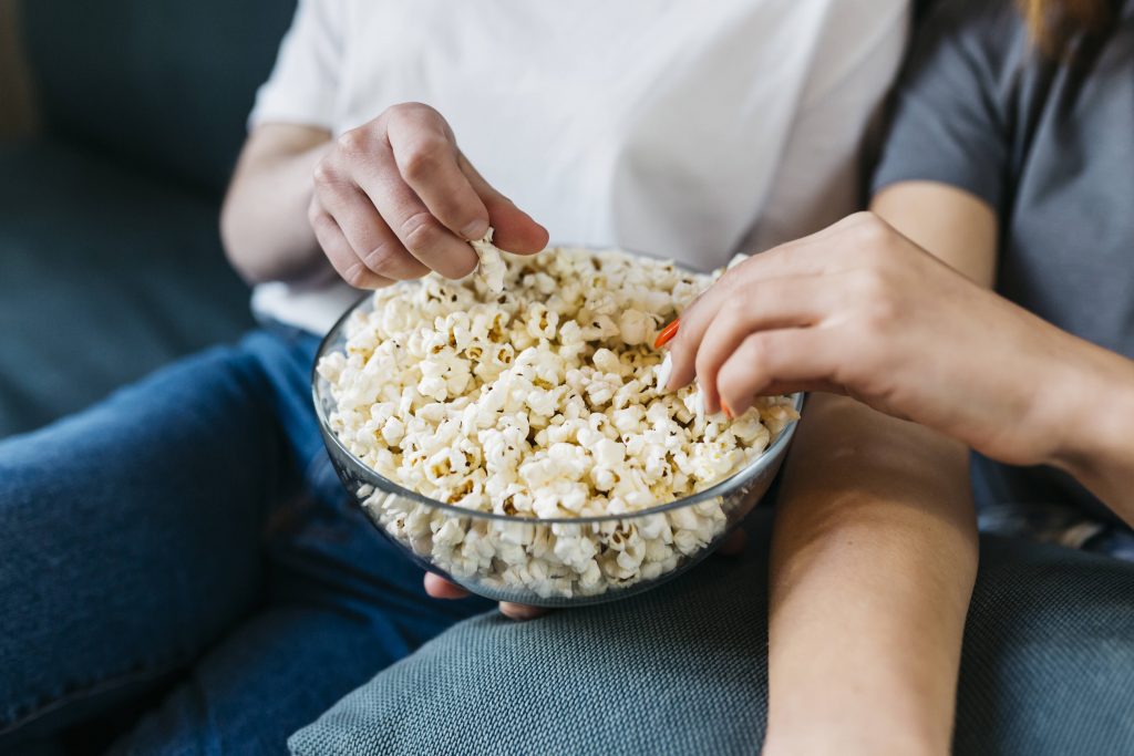 Zwei Personen greifen nach Popcorn.