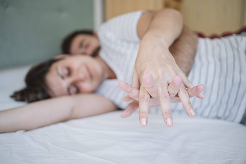 Pärchen liegt im Bett und hält Händchen