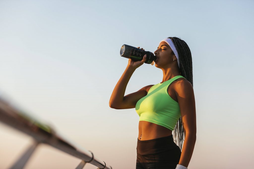 Frau trinkt nach dem Sport aus Wasserflasche