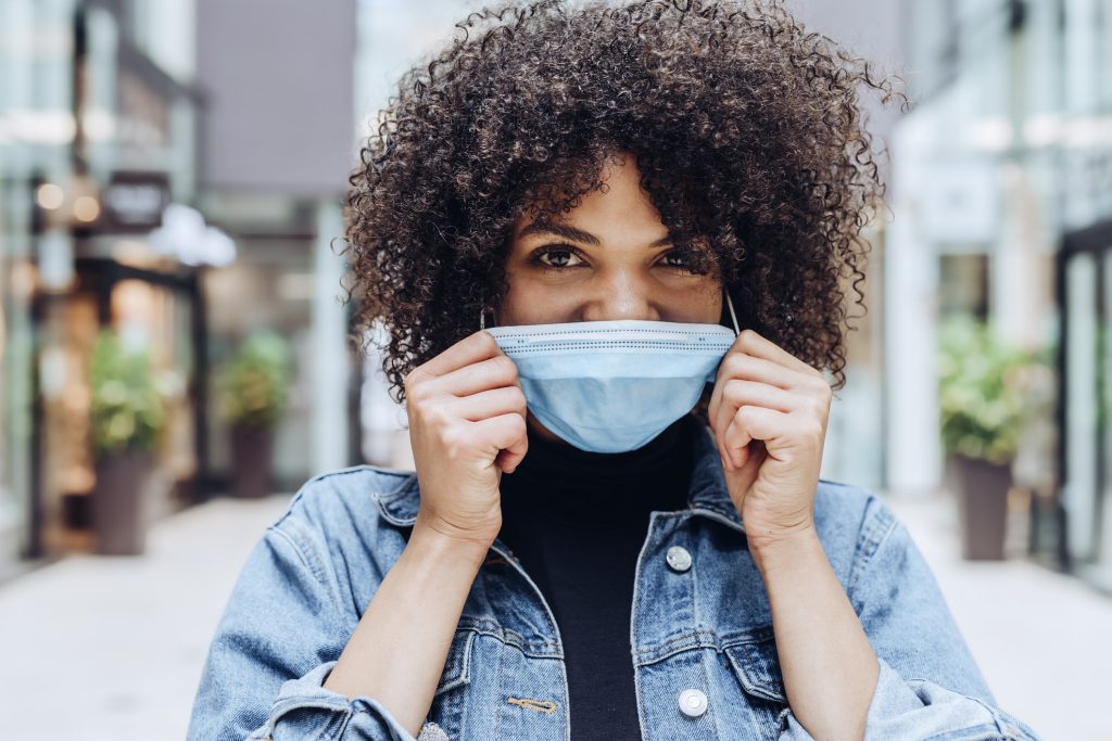 frau afro haare maske jeansjacke lächeln