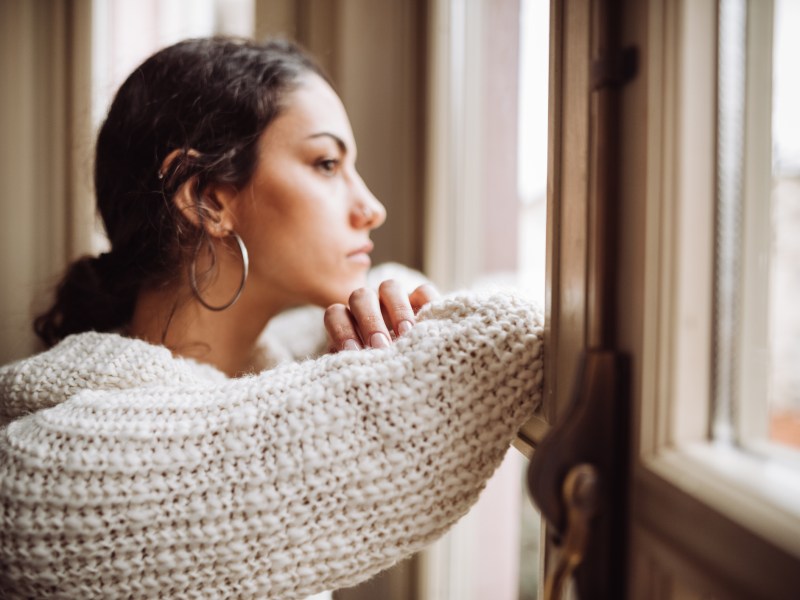 Weltschmerz Frau guckt traurig und nachdenklich aus dem Fenster