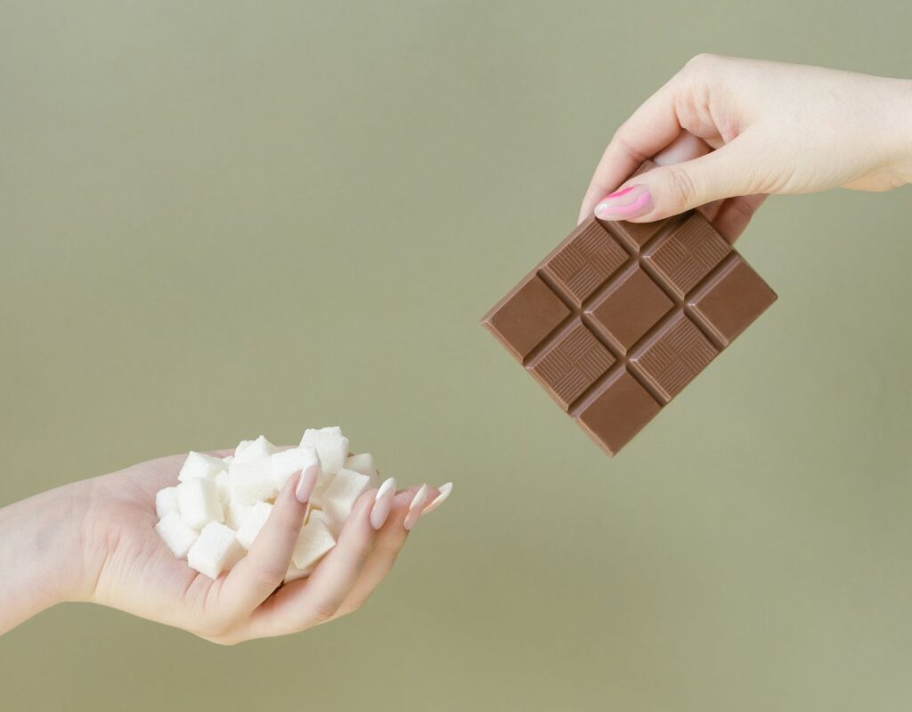 Hand reicht Zucker und Schokolade