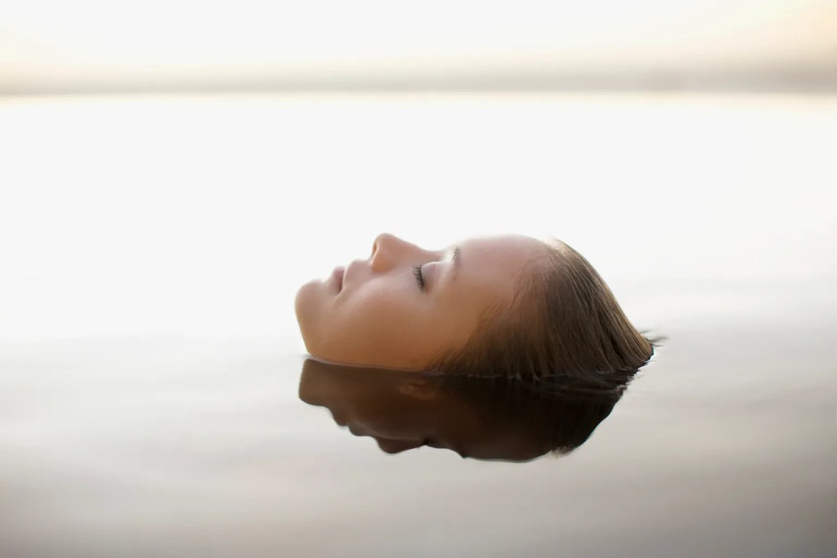 Frau liegt im Wasser.