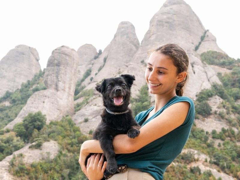 Lachende Frau mit Hund auf dem Arm