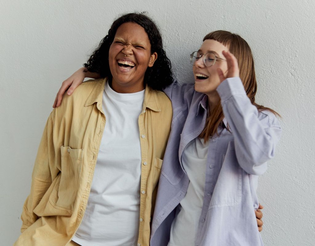 Zwei Frauen stehen nebeneinander und lachen