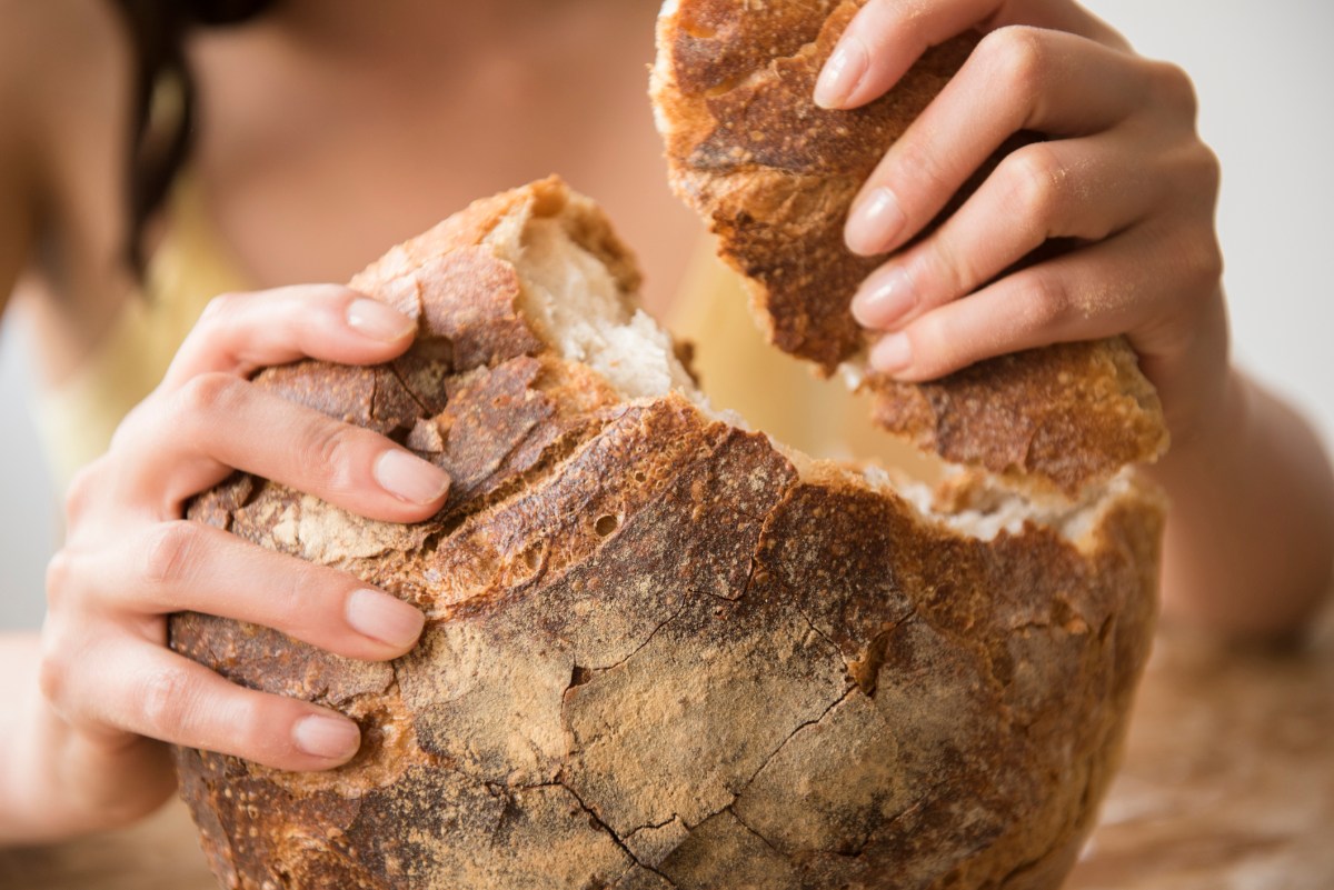 Frau reißt Stück von Brot ab