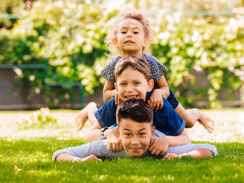 Sandwichkinder liegen auf dem Rasen übereinander