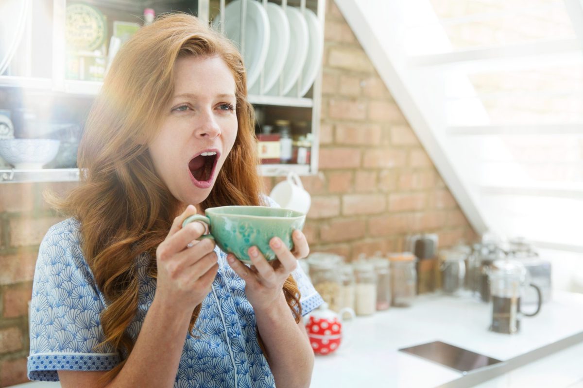 Frau gähnt mit Kaffee