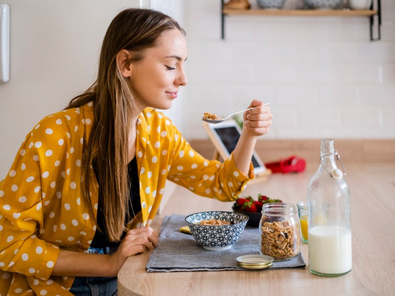 Frau isst Müsli mit Hafermilch