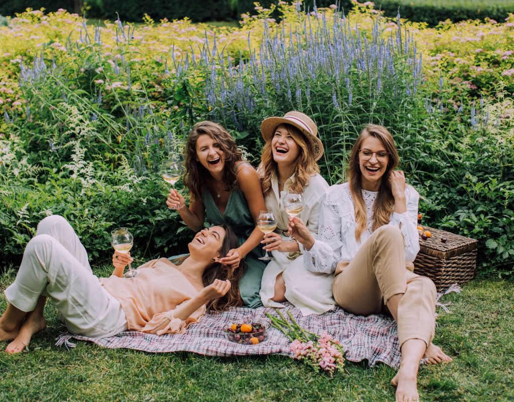 Frauen sitzen auf Decke und lachen