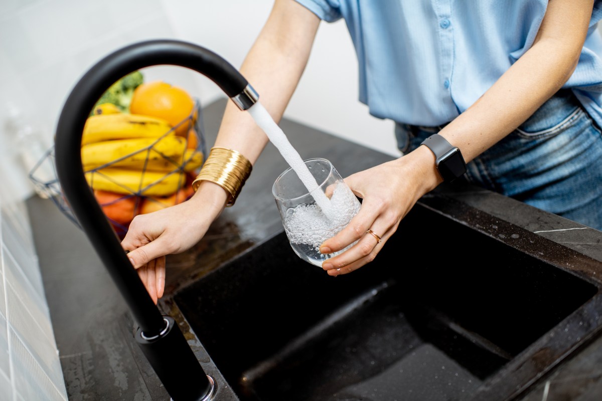 Frau trinkt aus Wasserhahn