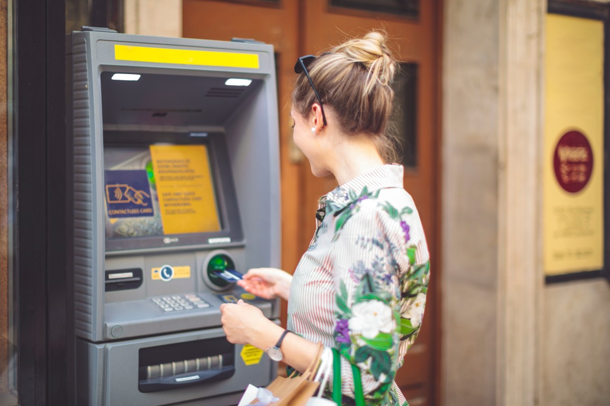 Frau hebt Geld am Automaten ab.