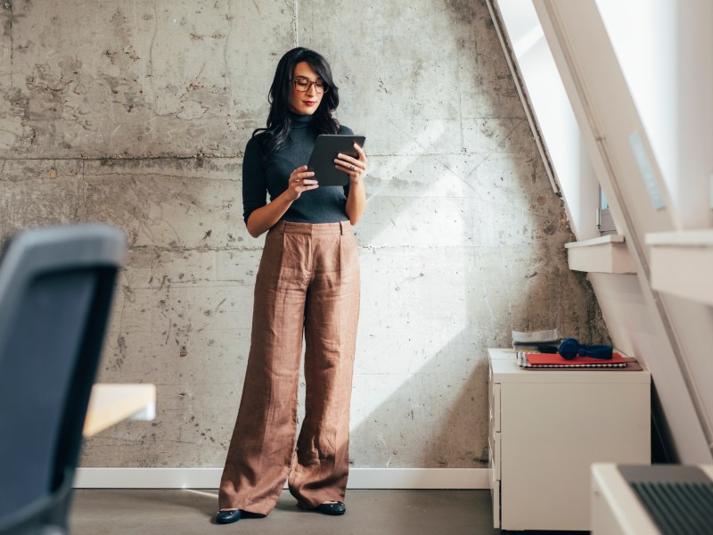 Eine Frau steht mit einem Tablet im Büro.