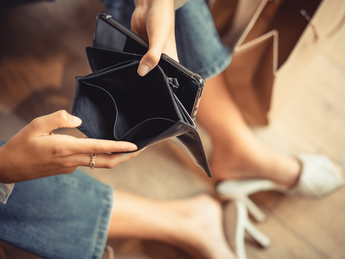 Frau hÃ¤lt leeres Portemonnaie in der Hand.