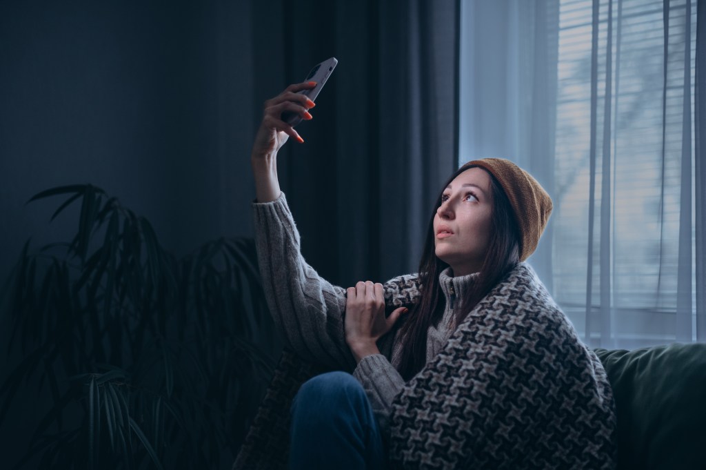 Junge Frau sucht mit ihrem Handy nach Empfang.