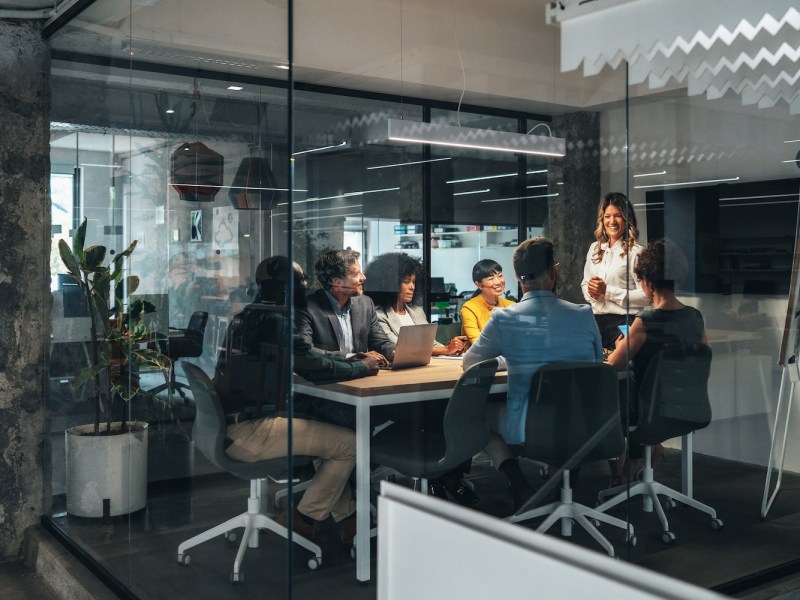 In einem Meetingraum sitzen mehrere Mitarbeitende.