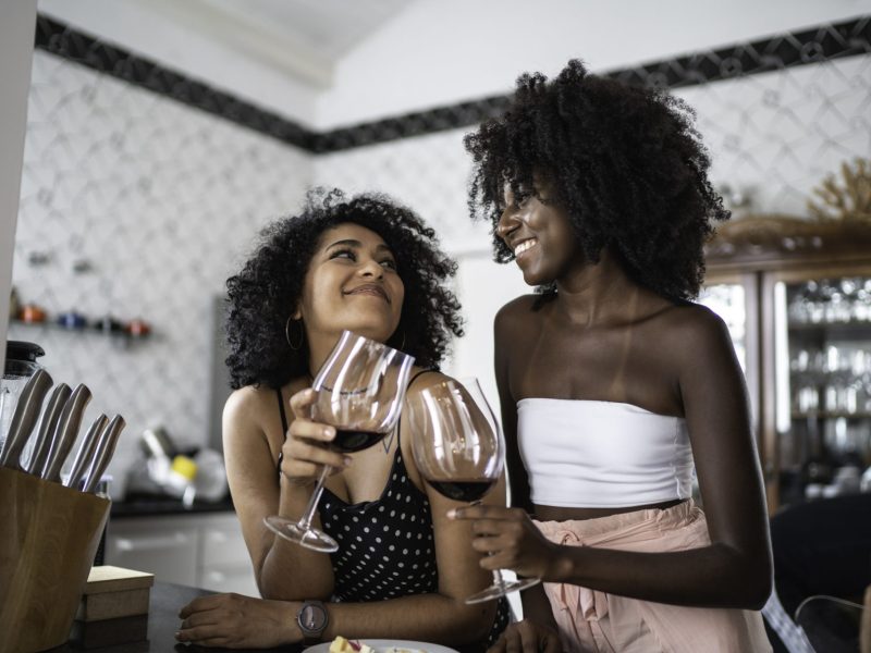 Zwei Frauen stoßen mit Rotwein an