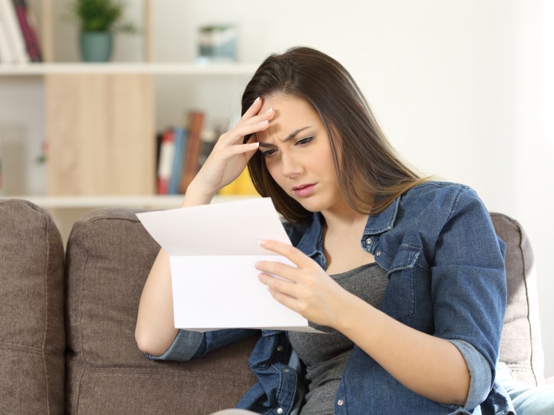 Frau hÃ¤lt Brief in der Hand und schaut verÃ¤rgert.