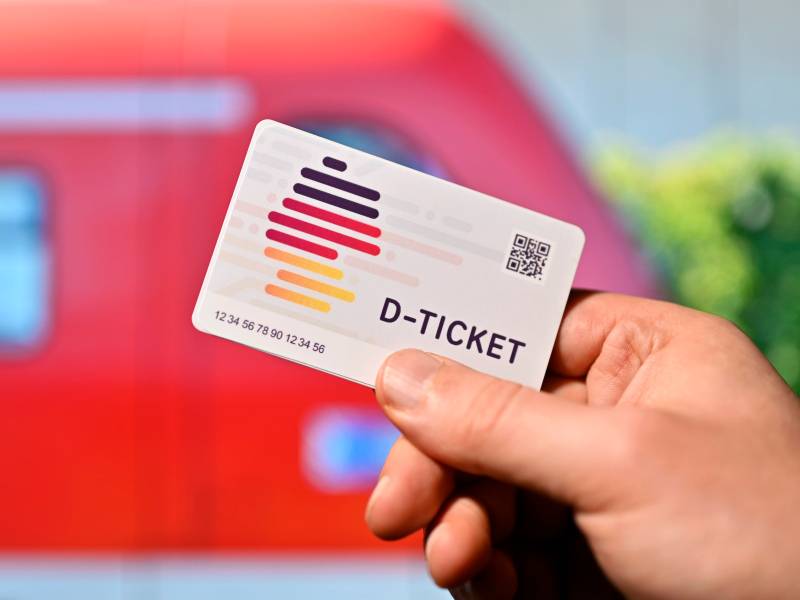 Eine Person hält eine Karte mit der Aufschrift "D-Ticket" in der Hand.