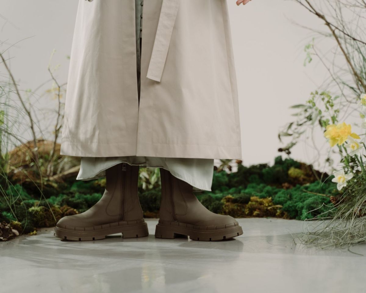 Frau steht mit Gummistiefeln zwischen Rasenflecken