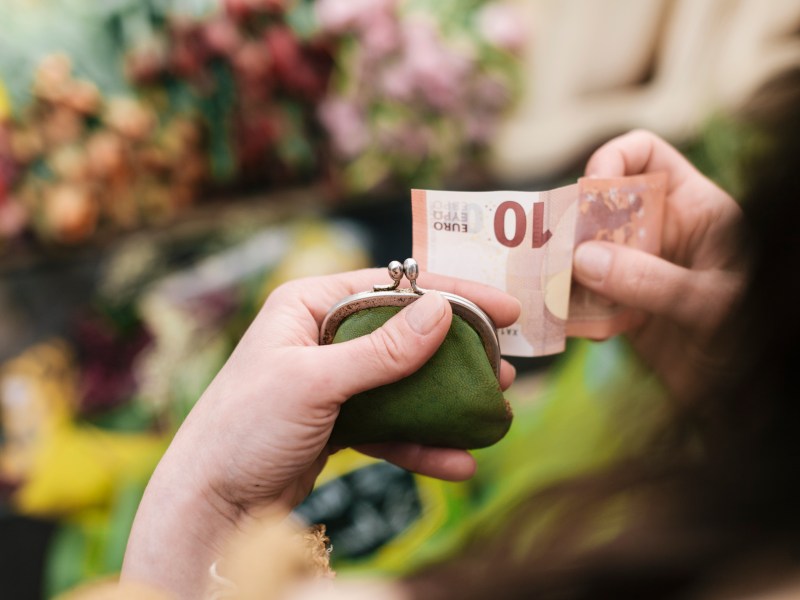 Frau hÃ¤lt einen Geldschein und ihr Portemonnaie in der Hand.