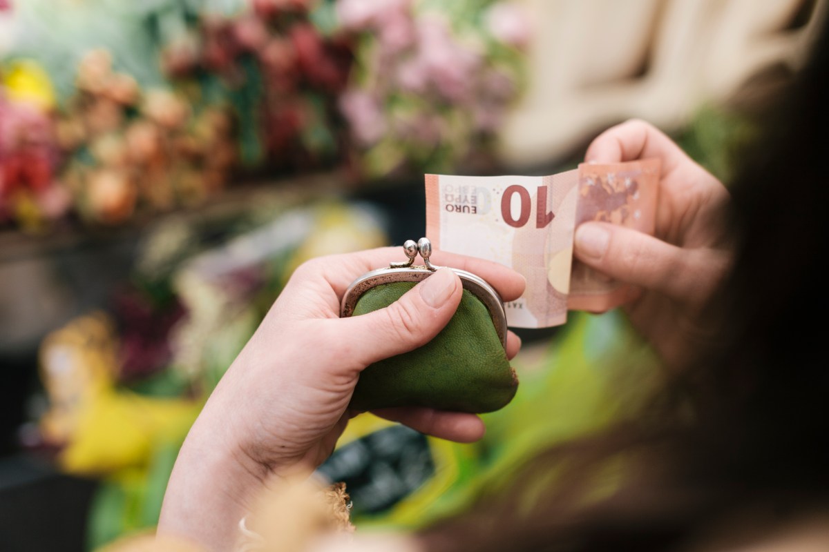 Frau hÃ¤lt einen Geldschein und ihr Portemonnaie in der Hand.