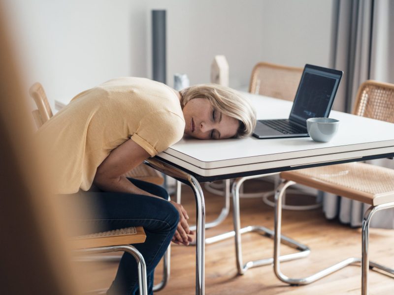 Frau schläft mit Kopf auf dem Tisch