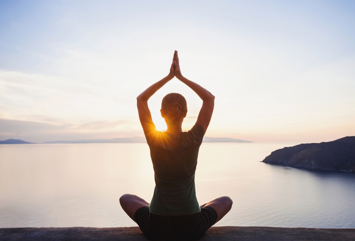 Frau macht Yoga im Sonnenuntergang.