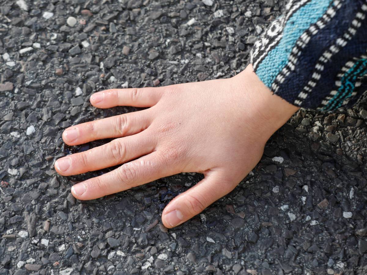 Hand klebt auf dem Asphalt.