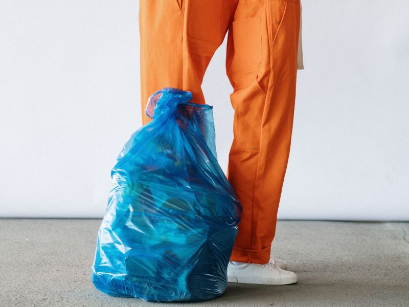 Zwei Menschen stehen hinter einer blauen Mülltüte.