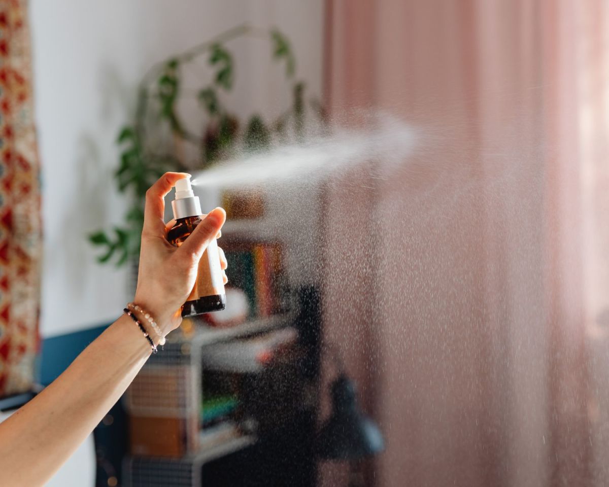 Frau sprüht ein Spray in einen Raum.