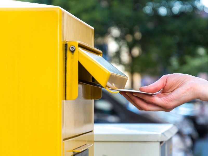 Person schmeißt einen Brief in einen Briefkasten der Deutschen Ost.